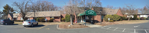 A view of a building featuring a green awning and surrounding landscaping.