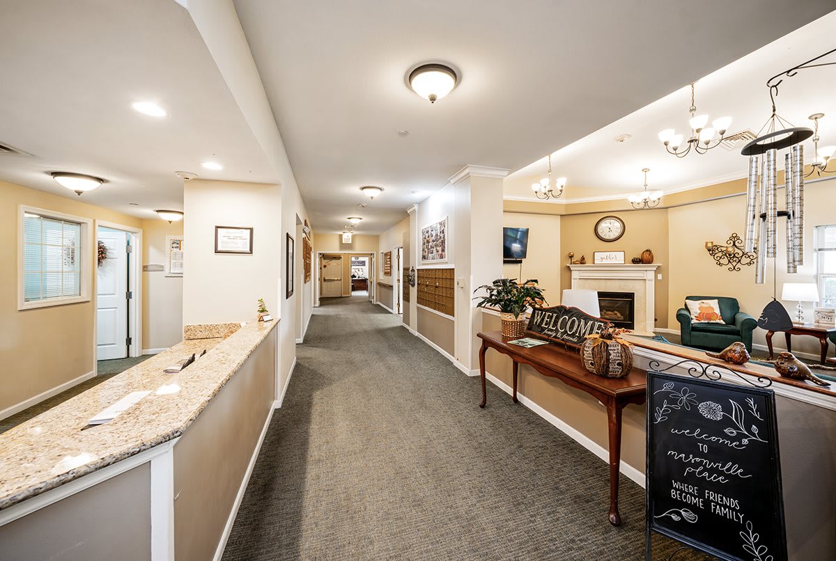 A well-lit hallway with carpeted floors and a reception area featuring decorative elements and furniture.