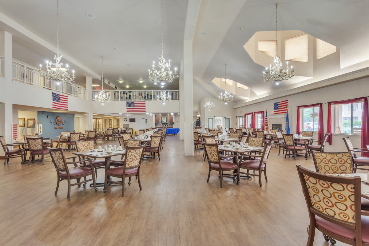 An elegant dining hall with chandeliers, featuring neatly arranged tables and chairs in a spacious setting.