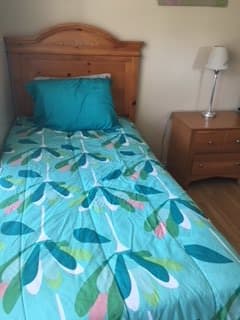 A neatly made bed with colorful bedding and a wooden nightstand with a lamp.
