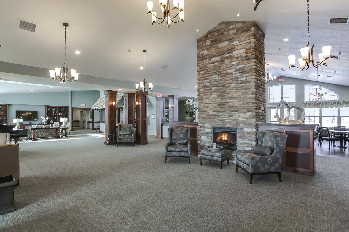 A spacious lobby with a central stone fireplace and comfortable seating surrounded by modern chandeliers.