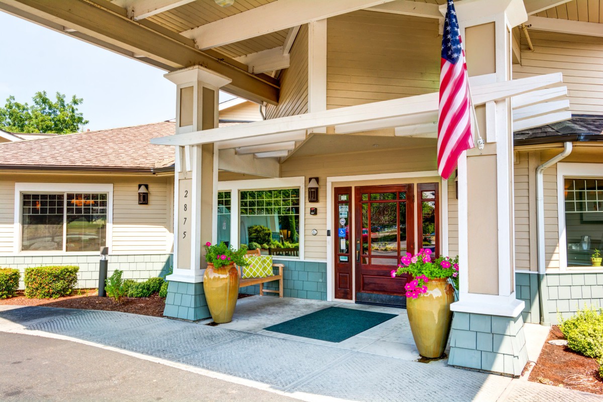 Entrance of a building with an American flag and potted plants by the door.