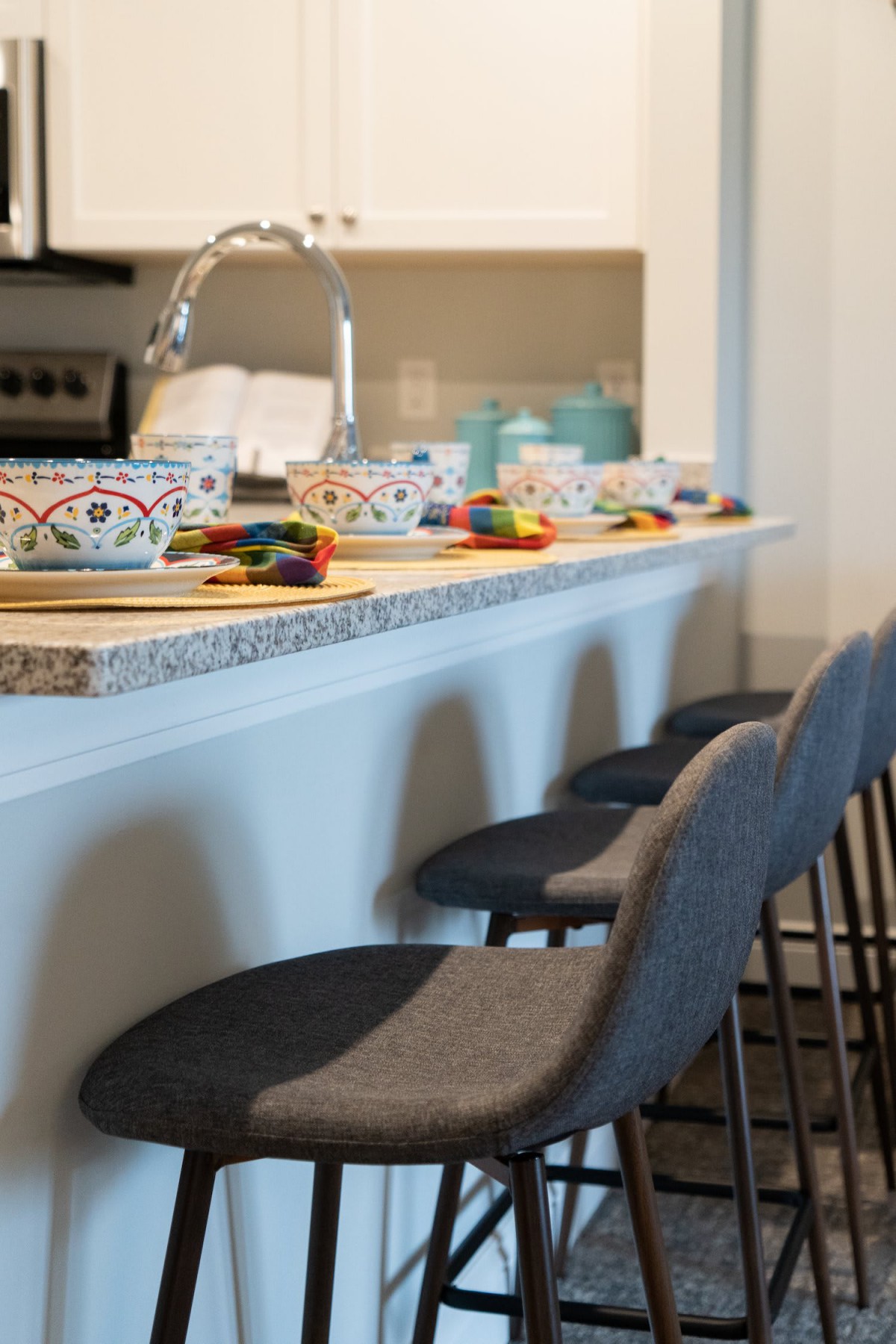 A modern kitchen with a countertop set for breakfast, featuring decorative mugs and sleek bar stools.