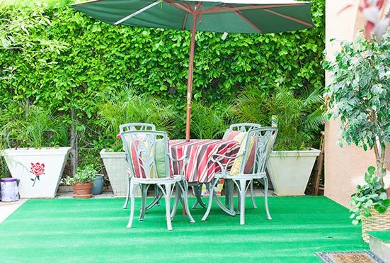 A colorful outdoor patio set with an umbrella amid lush greenery.