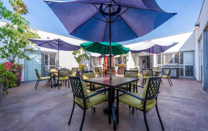 A sunny outdoor patio with tables, chairs, and colorful umbrellas.