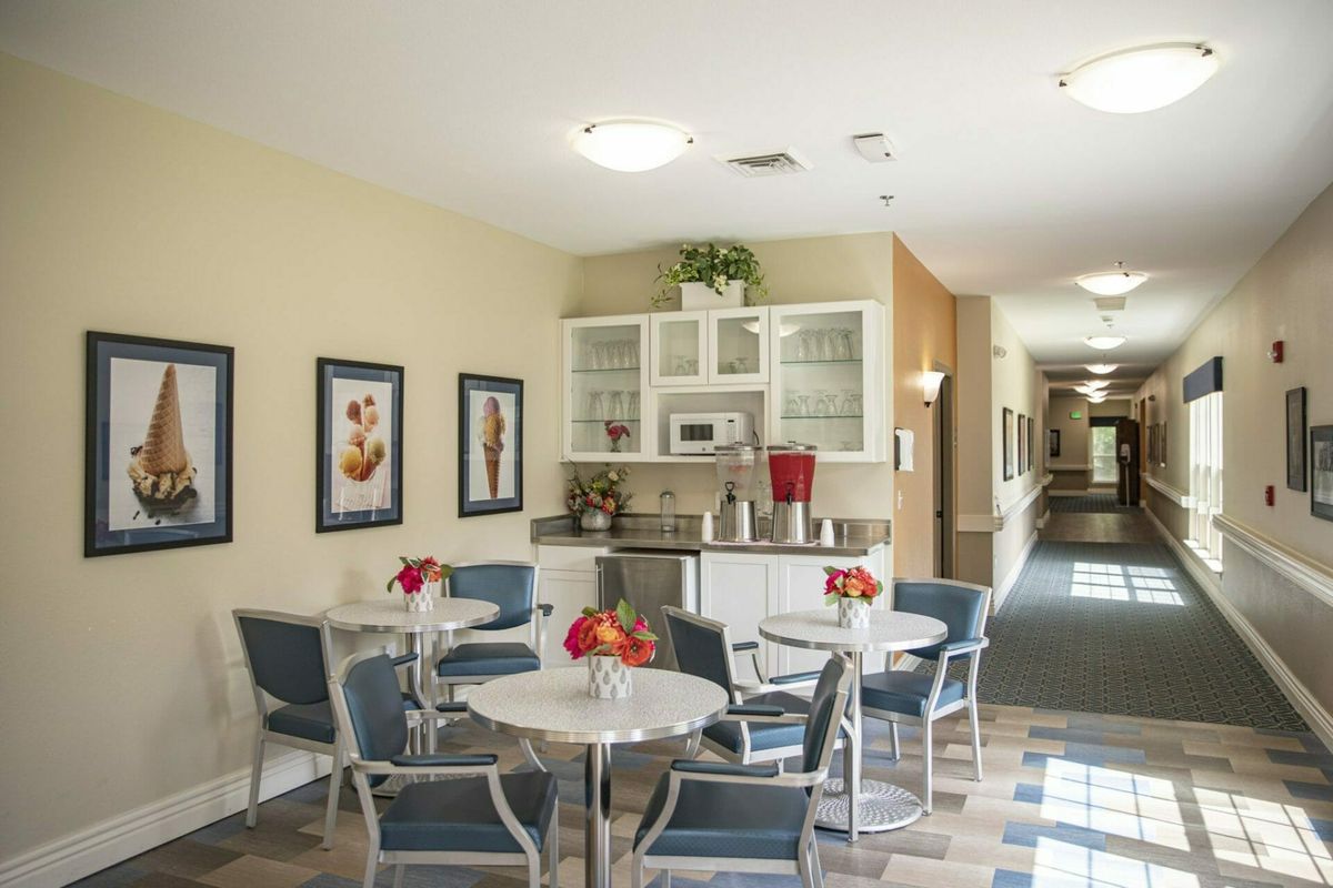 A modern and inviting dining area with tables, chairs, and a kitchenette in the background.