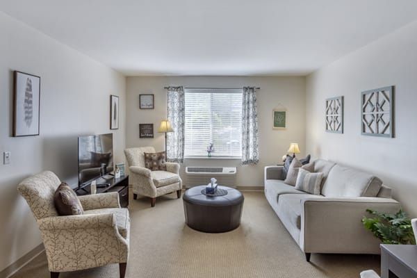 A cozy living room with a sofa, armchairs, and a round coffee table.