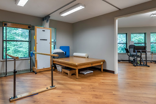 A spacious rehabilitation room featuring wooden flooring and exercise equipment.