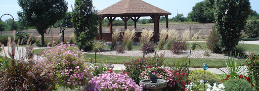 A serene garden featuring a wooden gazebo surrounded by colorful flowers and ornamental grasses.