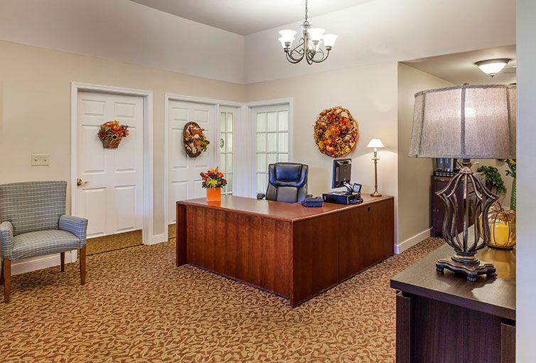 A warmly decorated office with autumn-themed accents, featuring a wooden desk, blue chair, and patterned carpet.