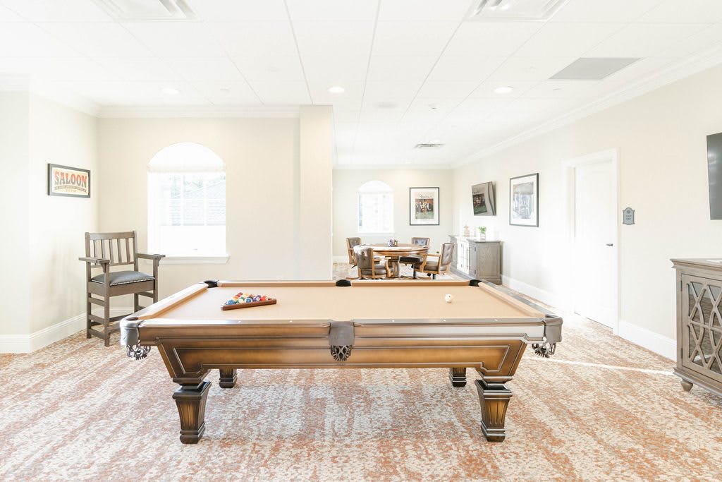 A well-lit game room featuring a wooden billiards table and elegant decor.