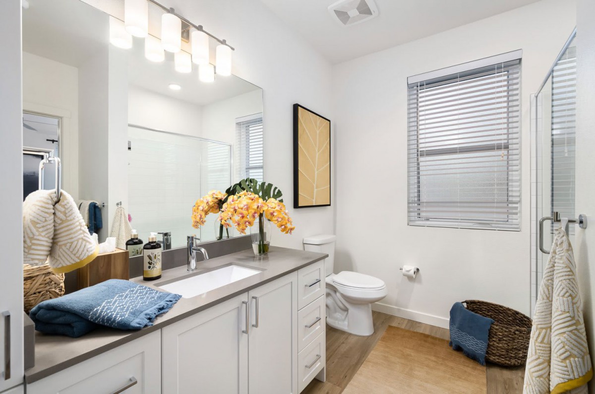A modern and clean bathroom with a well-decorated countertop featuring a vase of flowers.