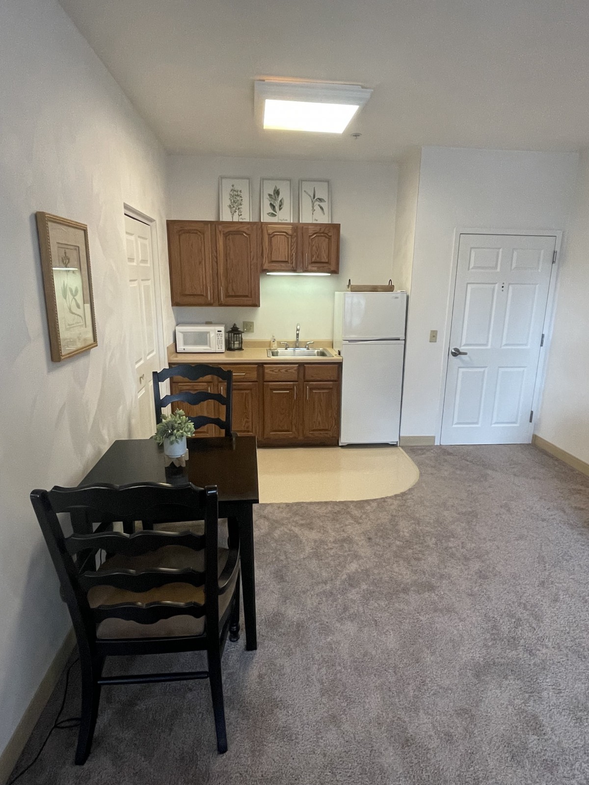 A compact kitchen with a small dining table, chairs, and essential appliances.
