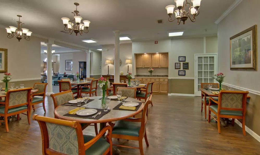 A spacious dining area with neatly set tables and elegant chandeliers.