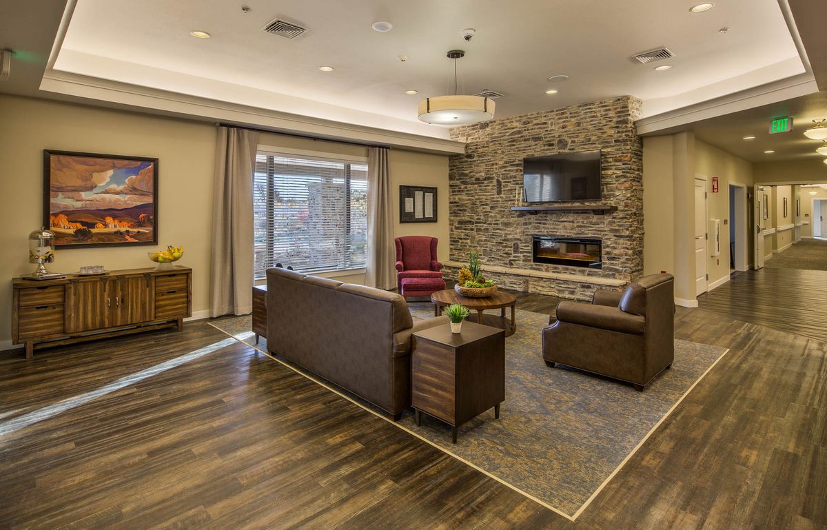 A modern living room with a stone fireplace, comfortable seating, and a mounted TV.