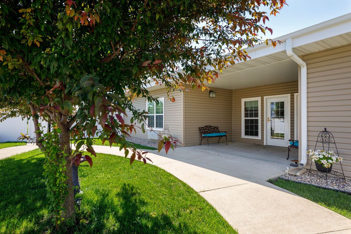 A welcoming building entrance with a sidewalk surrounded by greenery and trees.
