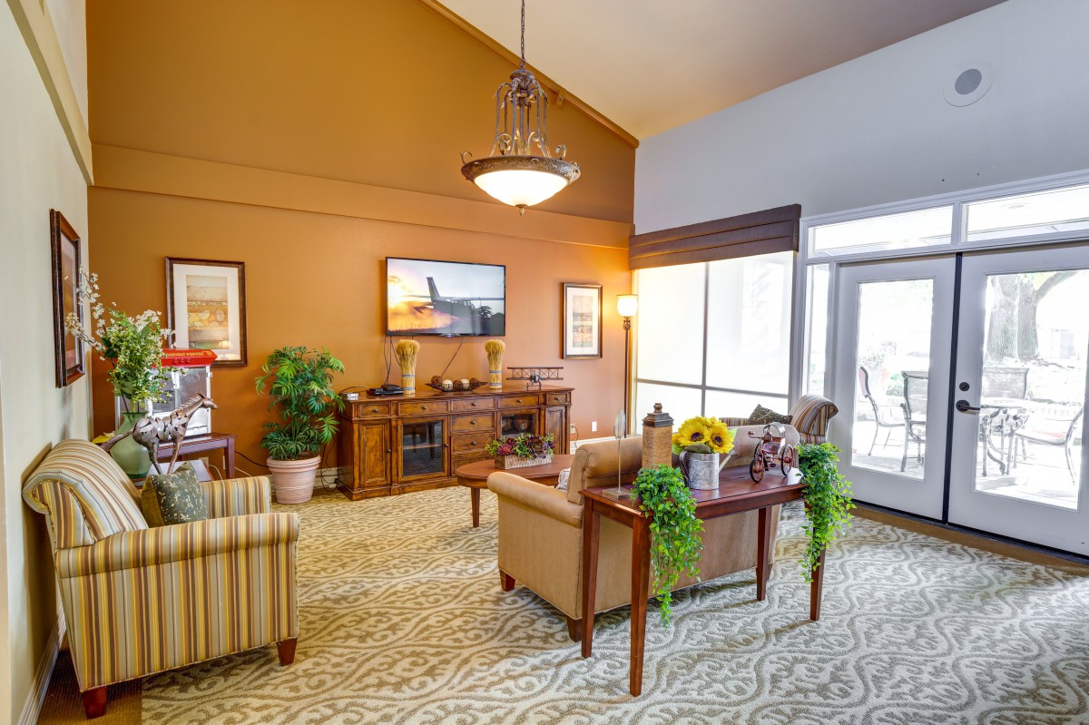 A cozy living room with warm tones, featuring comfortable seating, decorative plants, and elegant artwork.