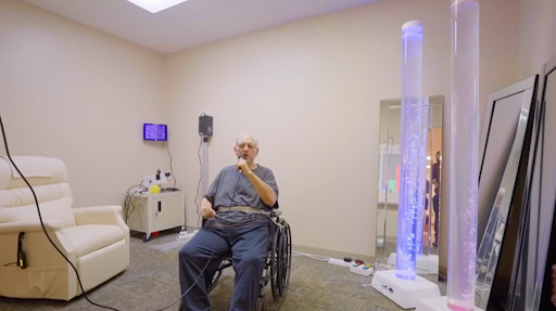 An elderly person sitting in a wheelchair in a rehabilitation setting, engaged in therapy.