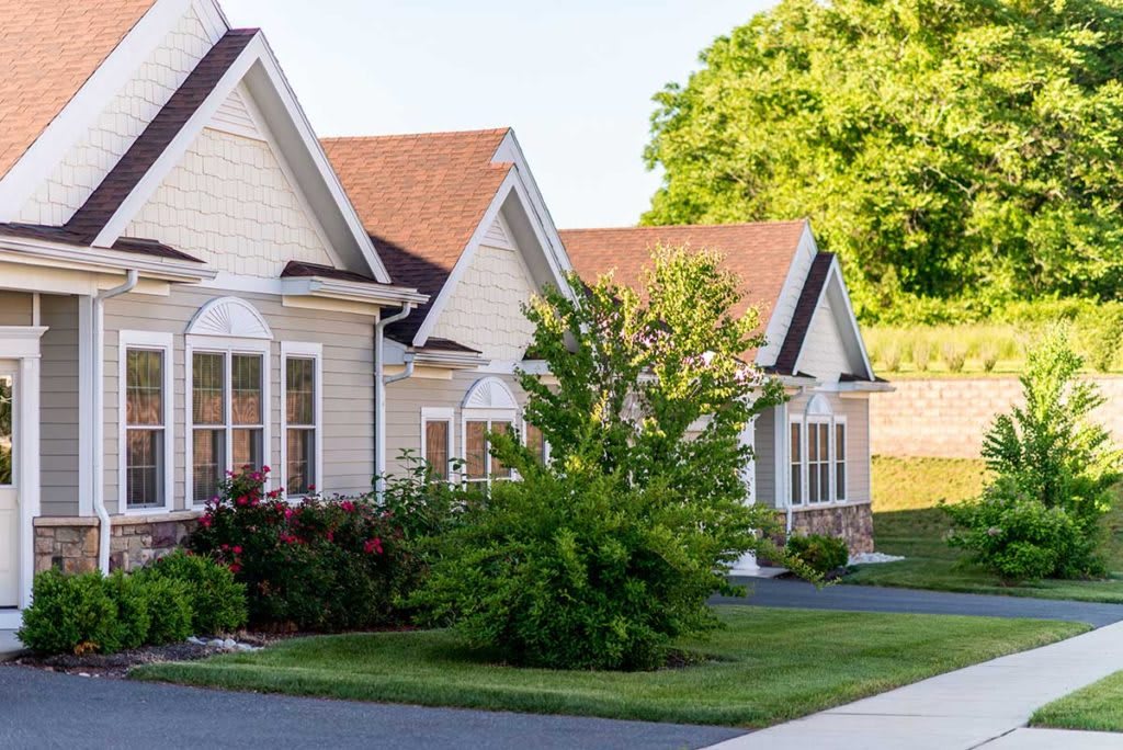 A row of suburban houses with well-maintained landscaping and driveways on a sunny day.