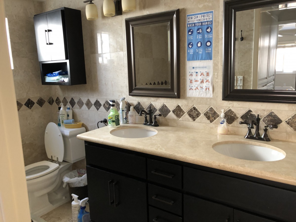 A well-organized bathroom featuring dual sinks, a toilet, and decorative tiles.
