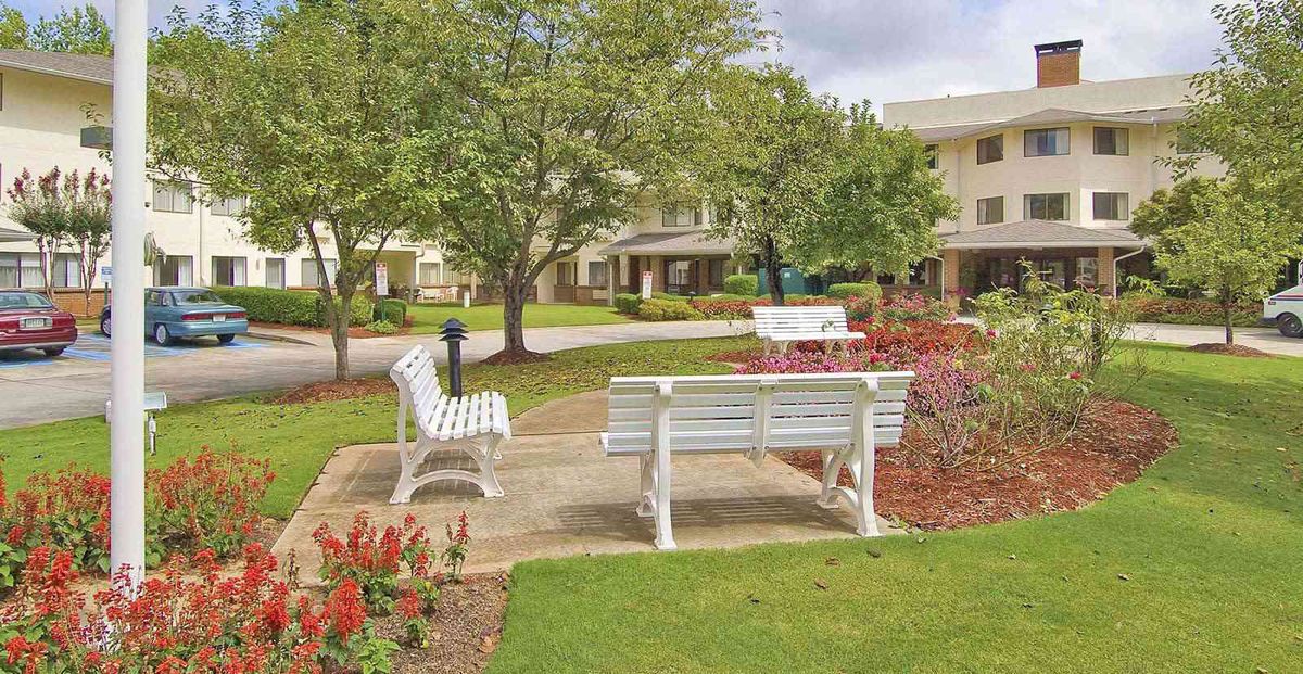 A peaceful park area with benches surrounded by trees and greenery.