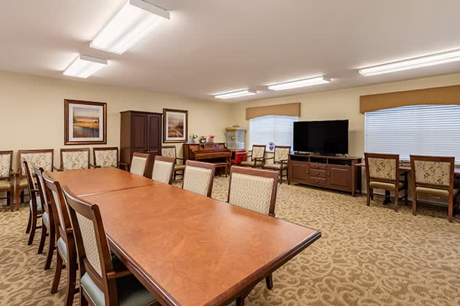A spacious conference room equipped with a large meeting table, several chairs, and a television.