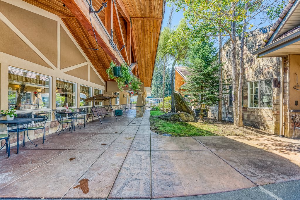 A modern architectural building with a spacious outdoor patio and surrounding trees.