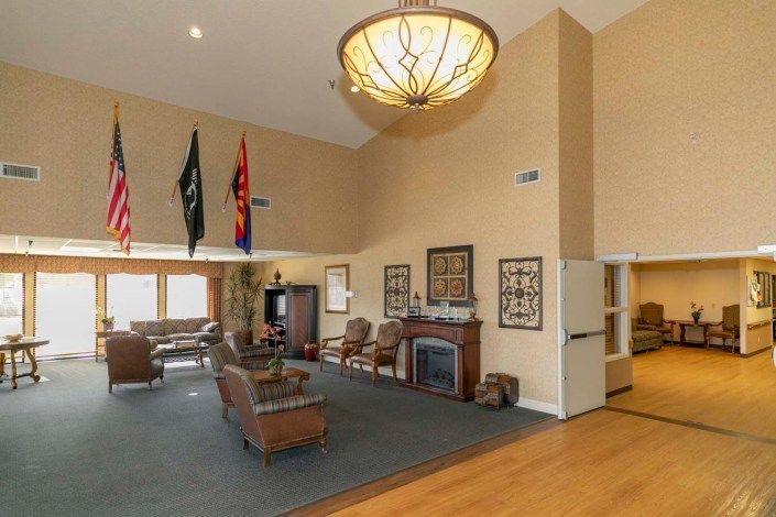 A spacious living room featuring a high ceiling, elegant chandelier, and comfortable seating around a fireplace.