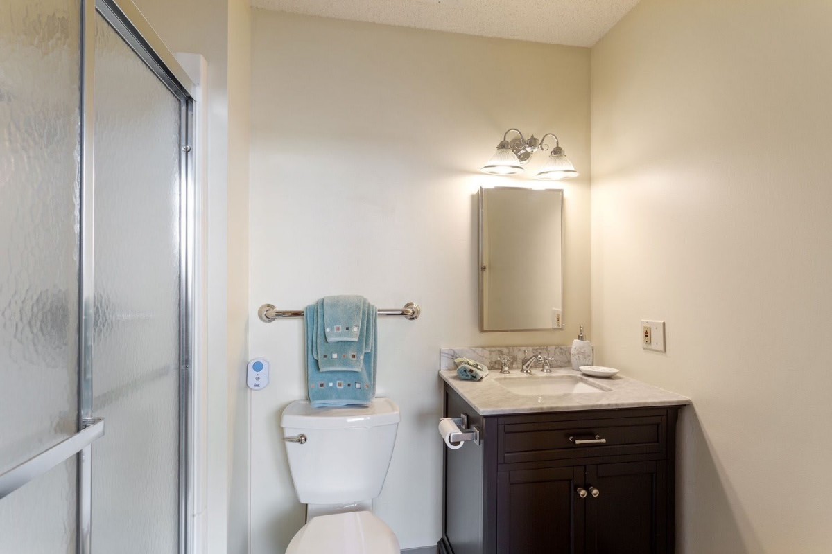A modern bathroom with a toilet, sink, mirror, and shower.