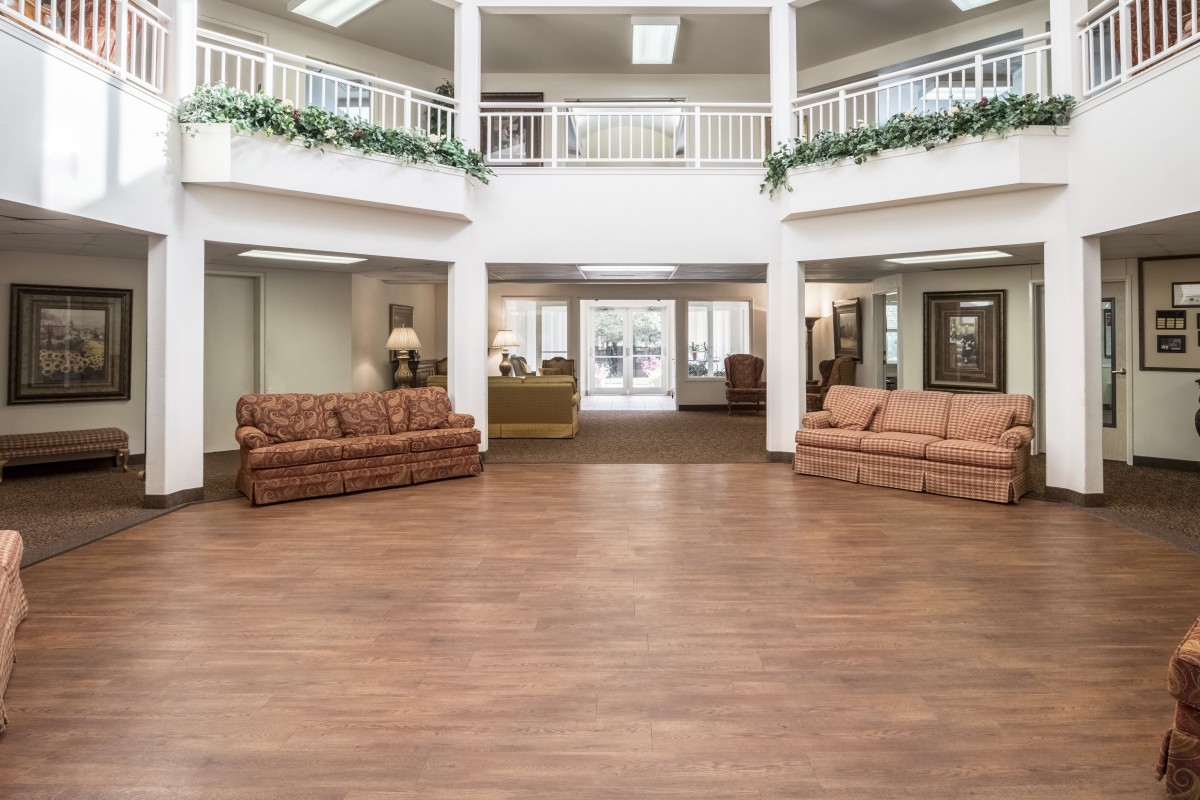Spacious lobby area with sofas and wooden flooring.