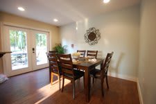 A cozy dining room featuring a wooden dining table with six chairs, complemented by wall art and illuminated by natural light.
