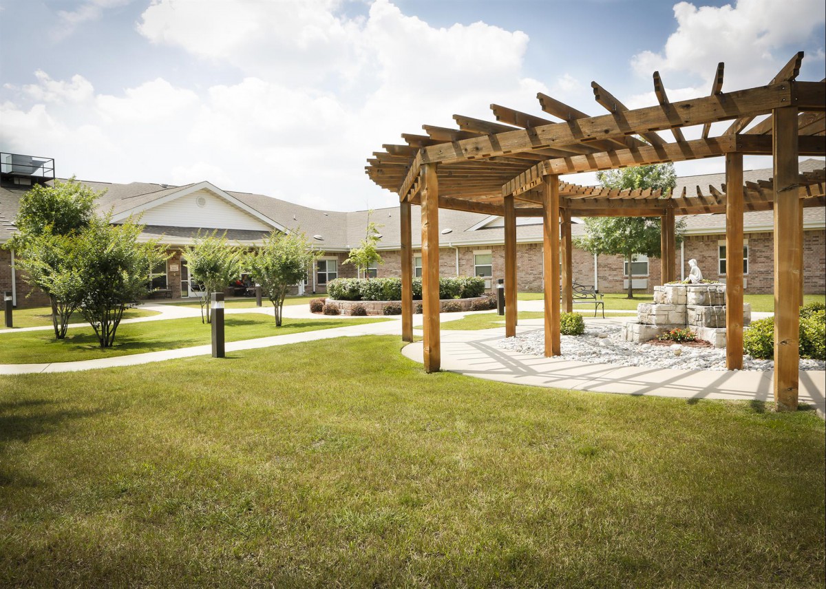 A well-maintained garden with a wooden pergola and a stone pathway on a sunny day.