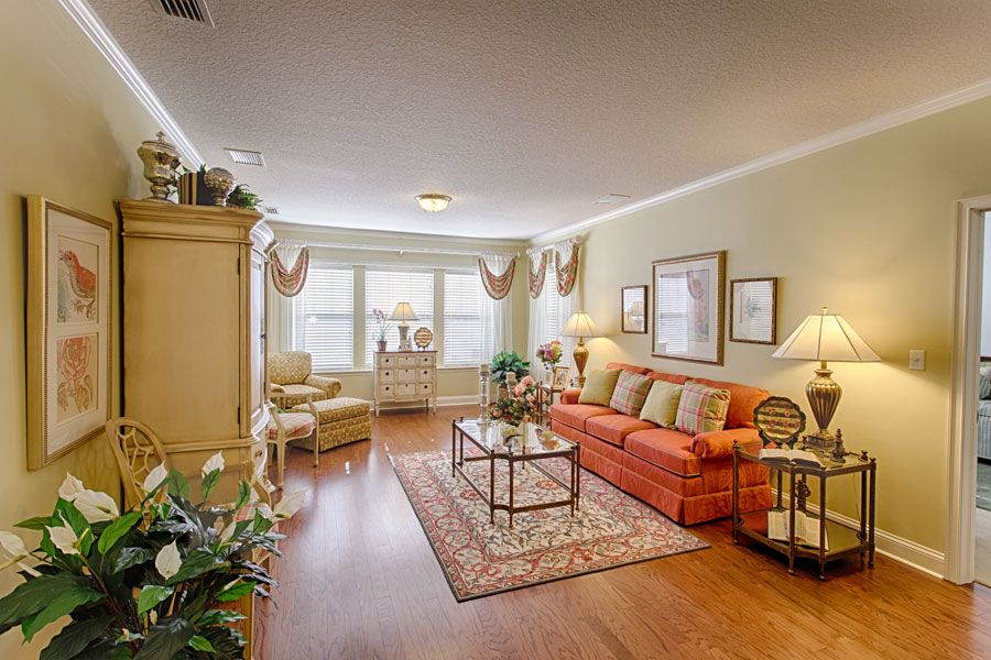 A cozy and well-decorated living room with a sofa, coffee table, and wooden flooring.