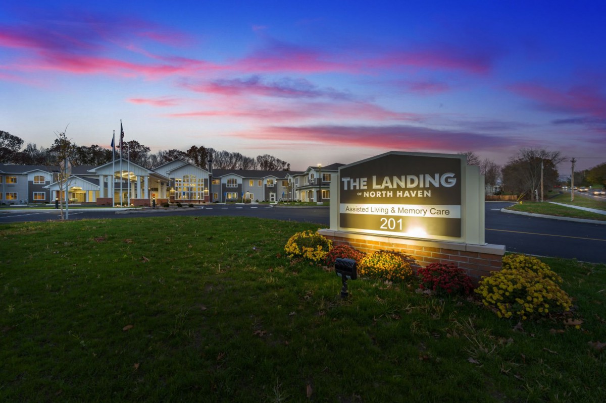 Entrance sign of 'The Landing' housing complex at sunset.