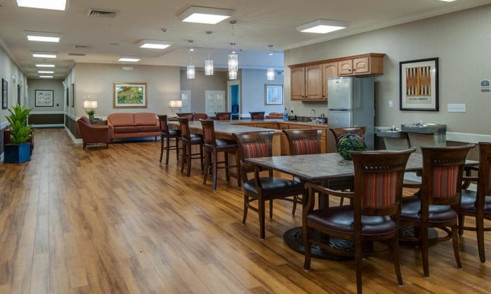 A cozy dining area with multiple tables and chairs, featuring a kitchen space in the background.