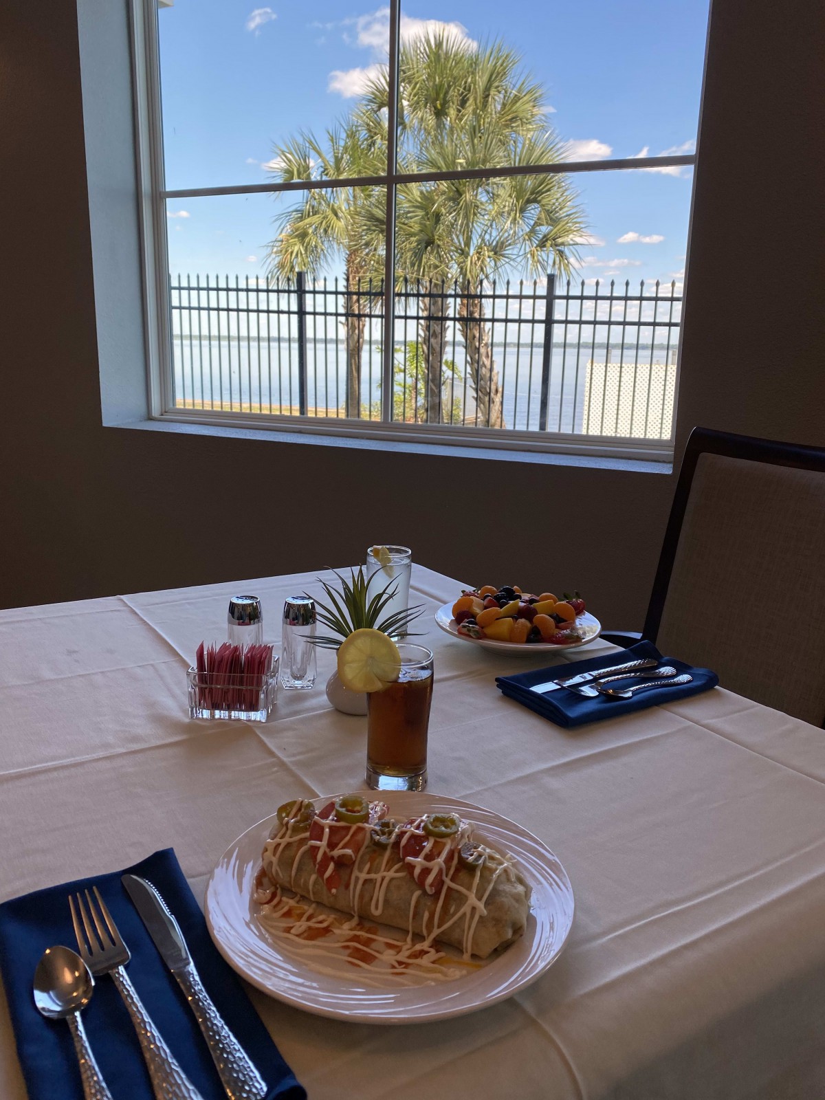 A beautifully set table with desserts and pastries, overlooking a palm tree through the window.