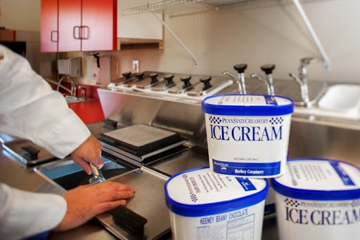 A chef scoops ice cream from tubs in a modern kitchen setting.