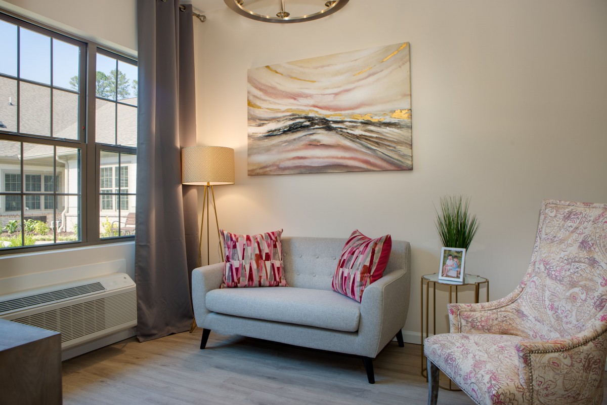 A cozy living room with a stylish sofa, abstract artwork on the wall, and decorative cushions.