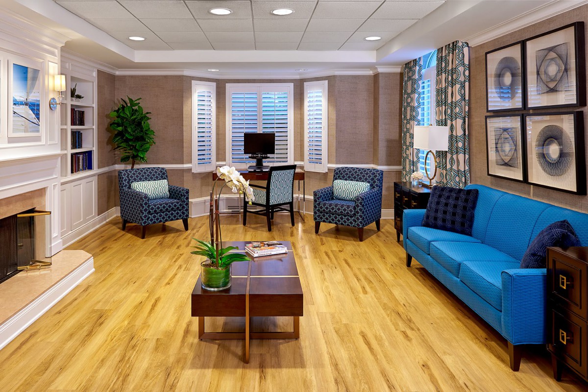 A modern living room with wooden flooring, stylish furniture, and large windows.