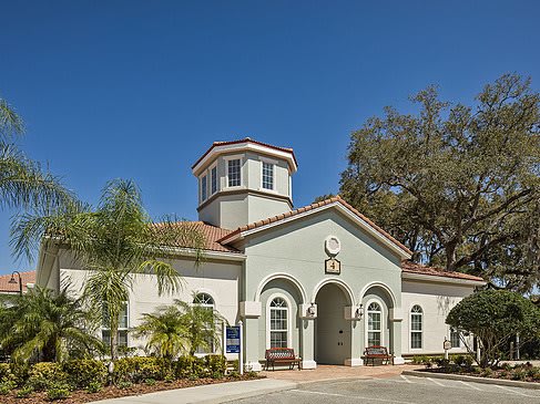 A sunny day view of a building with a tower and palm trees.