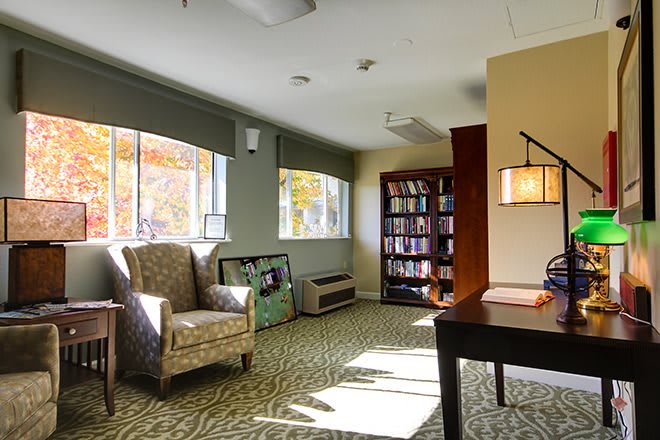 A cozy reading room with an armchair and a bookshelf.
