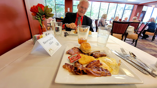 A hearty breakfast served at a senior dining venue, featuring bacon, eggs, and a biscuit.