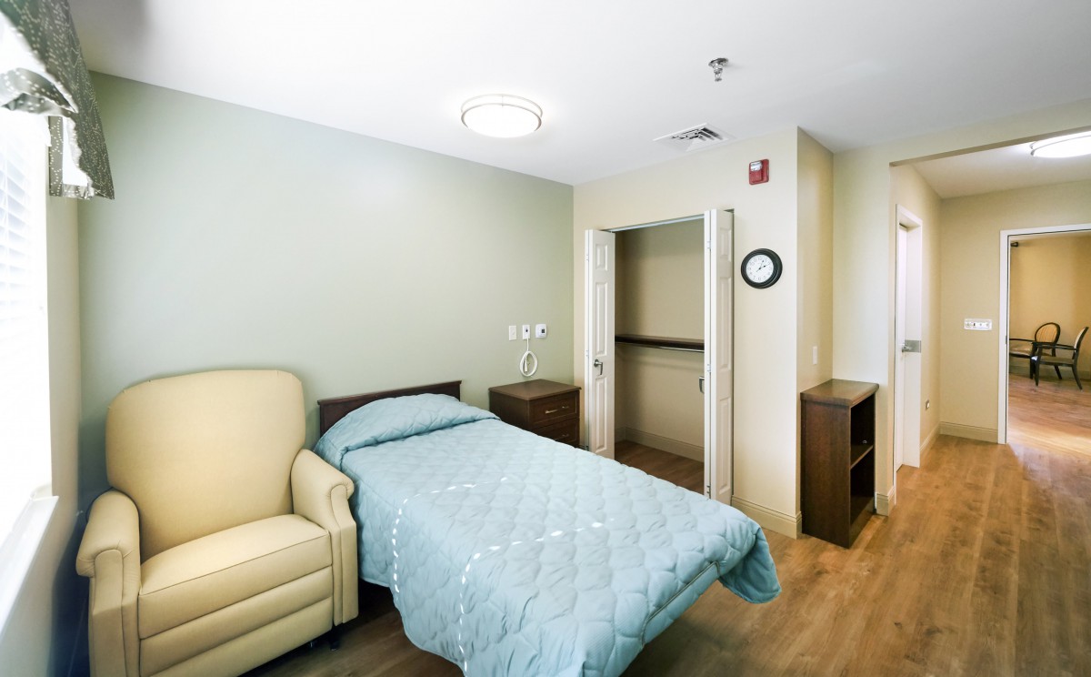 A minimalist hospital room with a single bed and chair.
