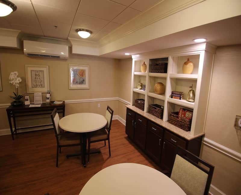 A cozy dining area with round tables, chairs, and decorative shelving.
