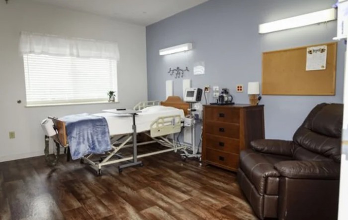 A modern hospital room featuring a bed, medical equipment, and comfortable furniture.