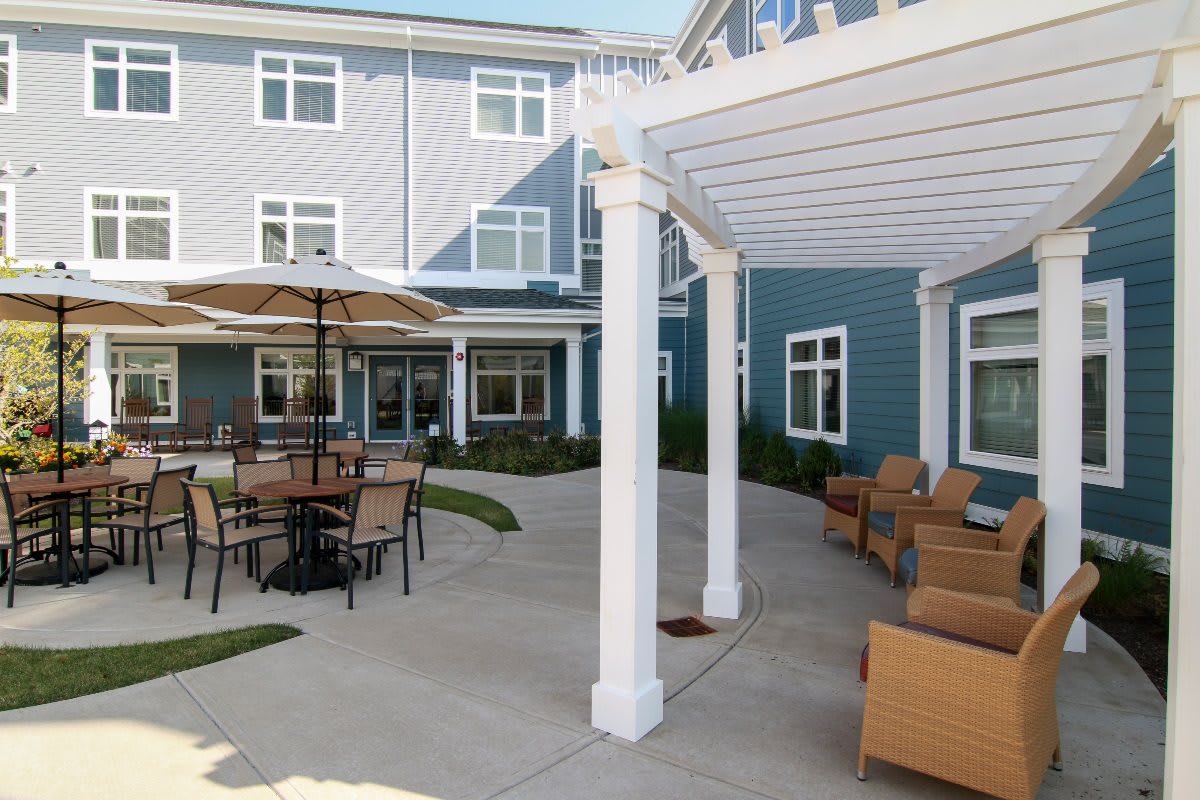 A modern courtyard with patio furniture and a pergola, surrounded by a building's exterior.