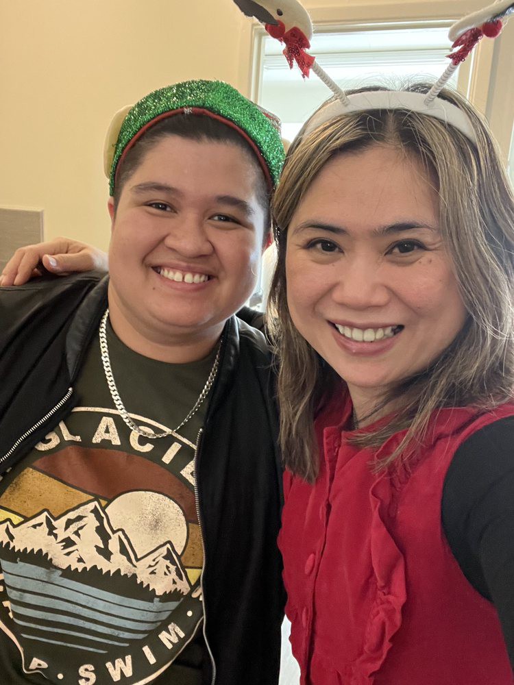 Two friends smiling together indoors, taking a selfie.