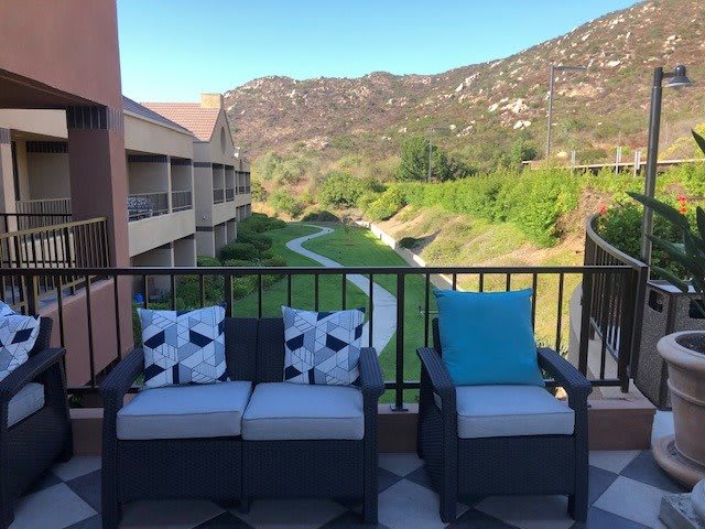 A scenic view from a balcony with comfortable seating and mountain landscape.