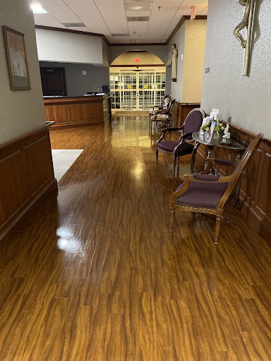 A well-lit hallway featuring wooden flooring and seating arrangements.