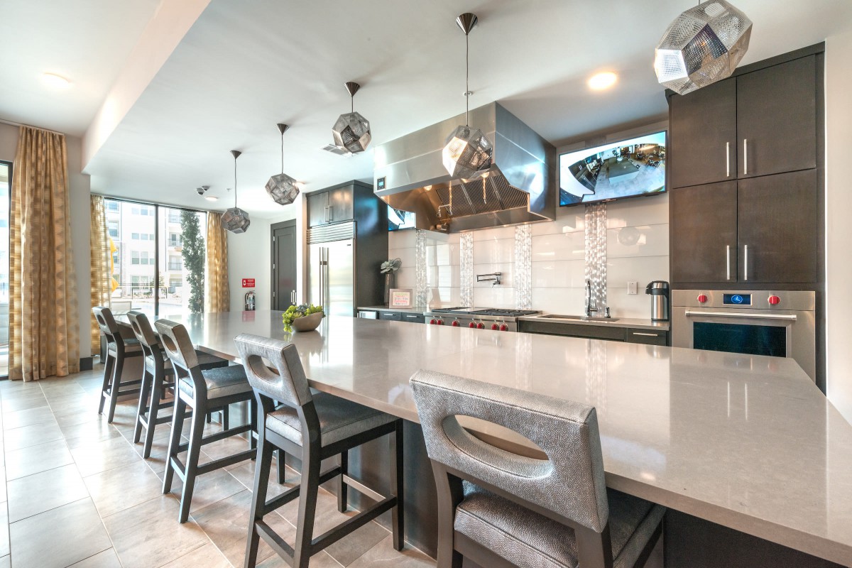 A modern kitchen interior featuring bar stools and pendant lighting.